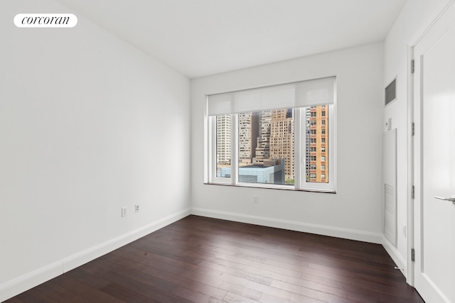 spare room featuring hardwood / wood-style floors and baseboards