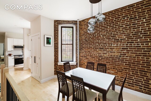 330 E 94th St Unit 1Ab, New York City, NY 10128 - dining area featuring brick wall, light wood-style floors, and baseboards