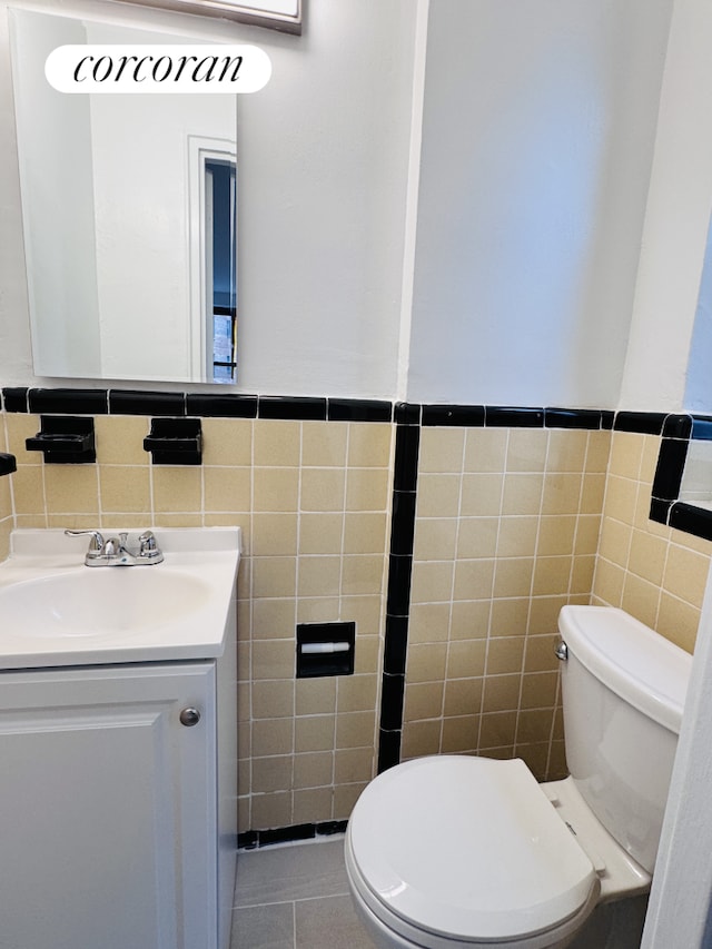 445 W 240th St Unit 4A, New York City, NY 10463 - bathroom featuring tile walls, vanity, toilet, a wainscoted wall, and tile patterned flooring