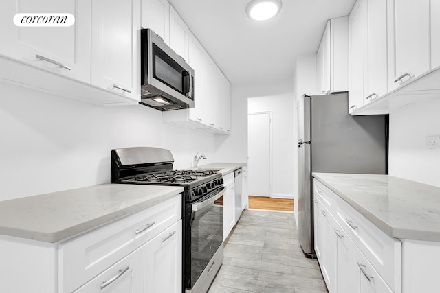 kitchen featuring stainless steel appliances, light wood-type flooring, white cabinets, and light stone countertops