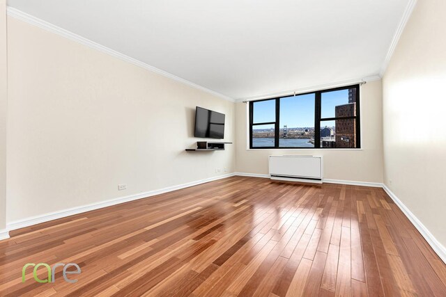340 E 93rd St Unit 28D, New York City, NY 10128 - unfurnished living room featuring crown molding, baseboards, and wood-type flooring