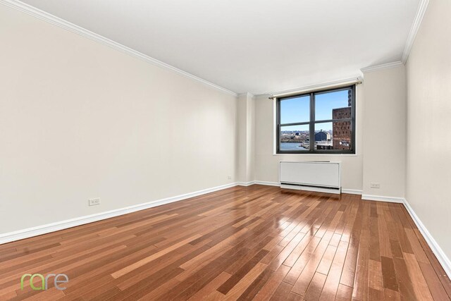 340 E 93rd St Unit 28D, New York City, NY 10128 - spare room with crown molding, baseboards, and wood-type flooring