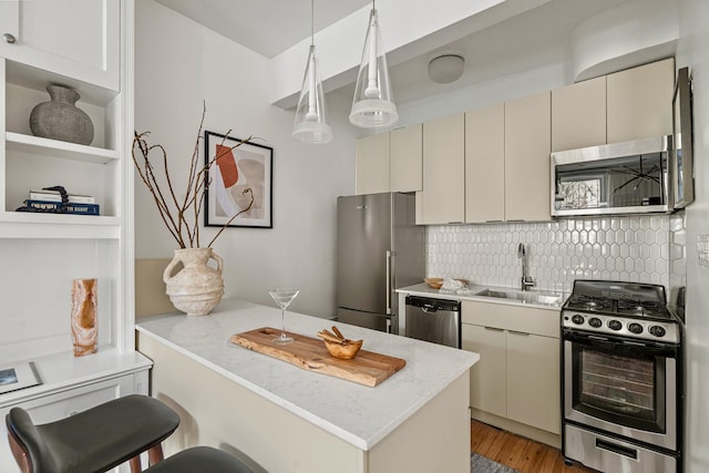 kitchen featuring light wood-type flooring, cream cabinets, tasteful backsplash, a sink, and stainless steel appliances