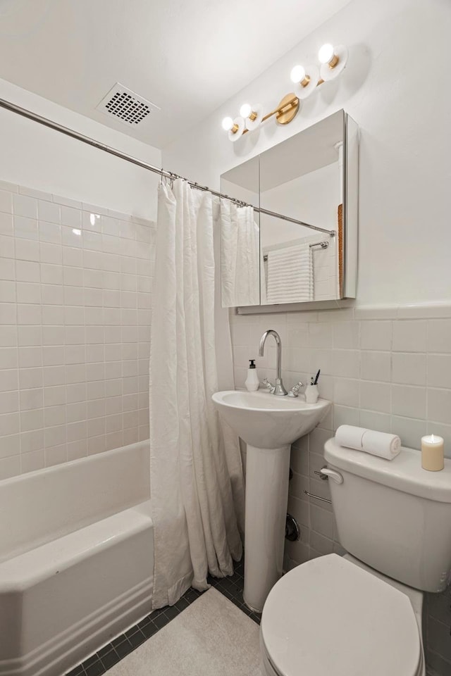 bathroom featuring shower / bath combo, toilet, tile patterned floors, tile walls, and visible vents