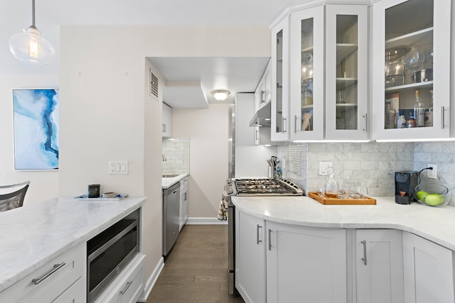 kitchen featuring white cabinets, stainless steel appliances, decorative backsplash, under cabinet range hood, and dark wood-style floors