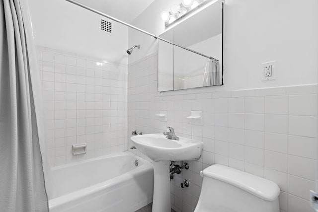 full bathroom featuring shower / tub combo, toilet, tile walls, and visible vents