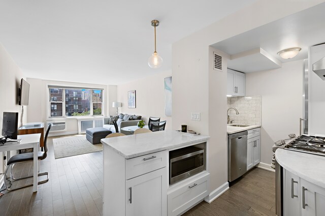 kitchen featuring appliances with stainless steel finishes, a sink, dark wood-type flooring, backsplash, and visible vents