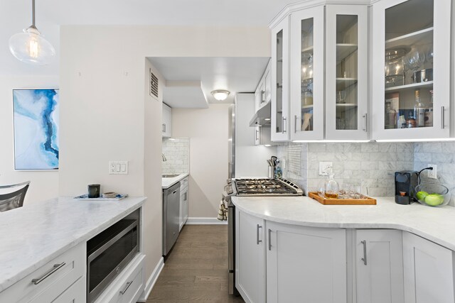435 E 77th St Unit 10E, New York City, NY 10075 - kitchen with stainless steel appliances, under cabinet range hood, white cabinets, tasteful backsplash, and dark wood-style flooring