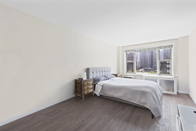 bedroom with baseboards, radiator, and wood finished floors