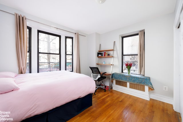 bedroom featuring baseboards, multiple windows, and hardwood / wood-style flooring