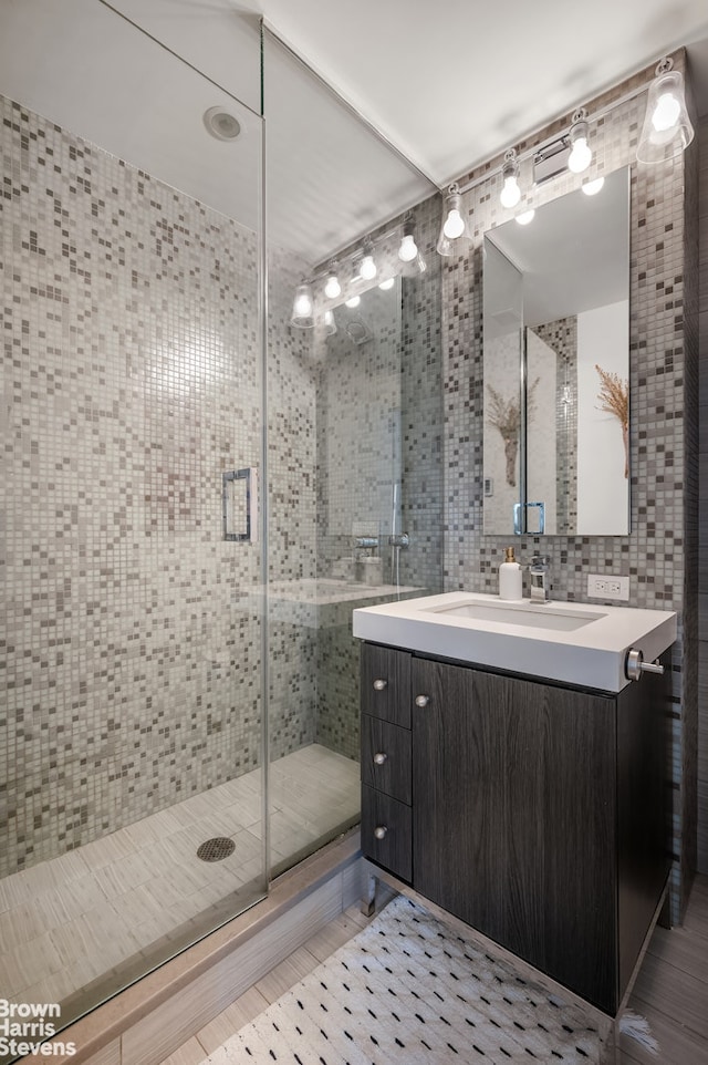432 W 52nd St Unit 7H, New York City, NY 10019 - bathroom with tile walls, vanity, a stall shower, and wood finished floors