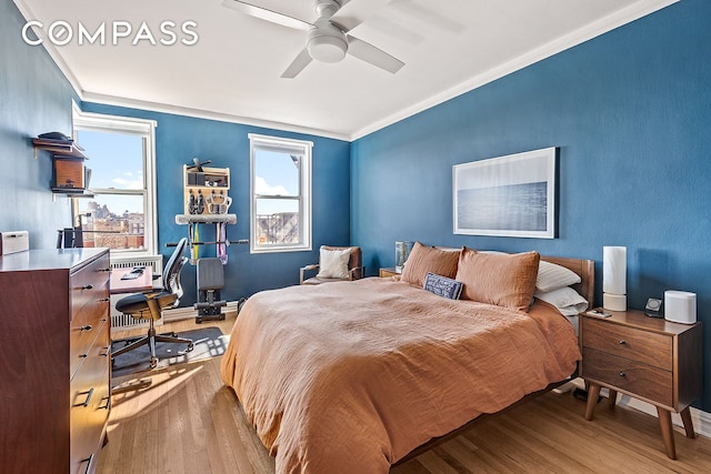 bedroom featuring crown molding, baseboards, ceiling fan, and wood finished floors