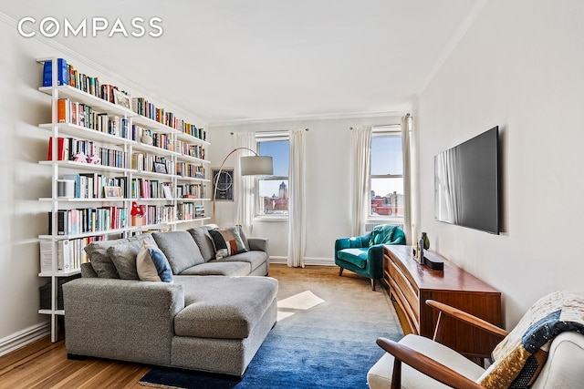 sitting room with baseboards, ornamental molding, and wood finished floors