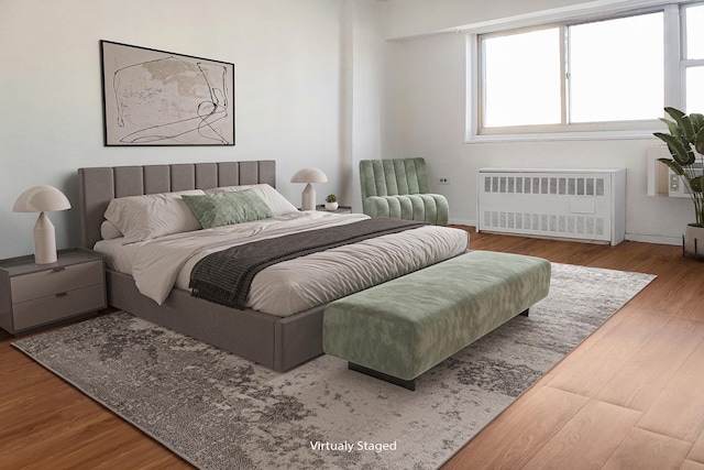 bedroom featuring radiator, wood finished floors, and baseboards