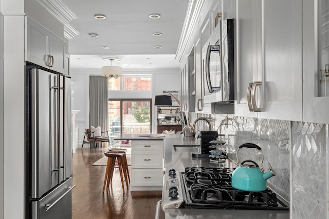428 W 23rd St Unit 1A, New York City, NY 10011 - kitchen with dark wood-style flooring, crown molding, appliances with stainless steel finishes, a sink, and white cabinets
