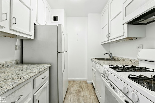 kitchen with range hood, white appliances, visible vents, a sink, and white cabinets