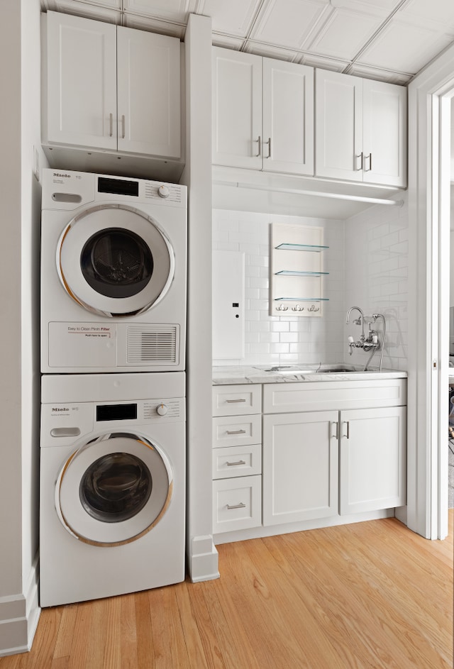 laundry room featuring estacked washer and dryer and light wood finished floors