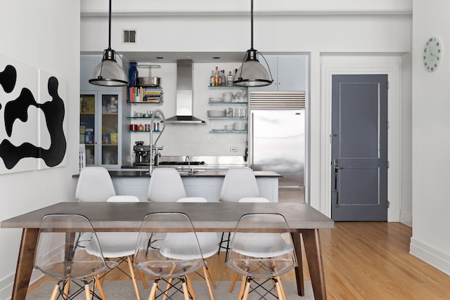 dining space with light wood-style floors, baseboards, and bar area