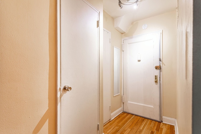 doorway featuring baseboards and light wood-type flooring
