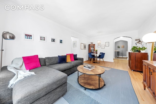 living room with arched walkways and light wood-style flooring