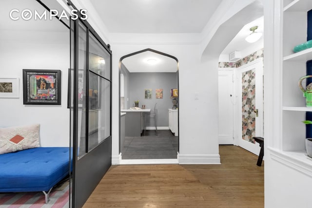 interior space with baseboards, a barn door, and wood finished floors