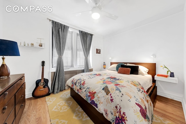 bedroom with a ceiling fan, baseboards, and light wood-style flooring