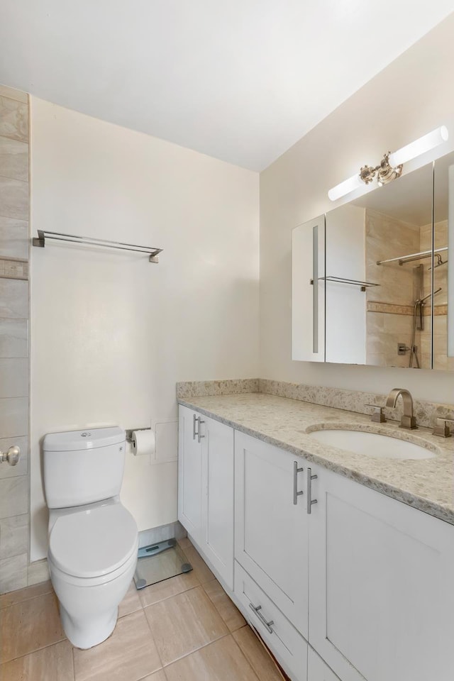 bathroom with a tile shower, vanity, tile patterned flooring, toilet, and baseboards