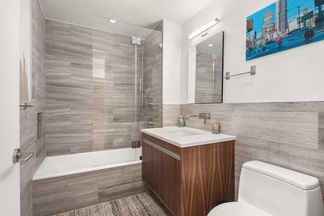 full bathroom featuring tiled shower / bath combo, toilet, tile walls, and vanity