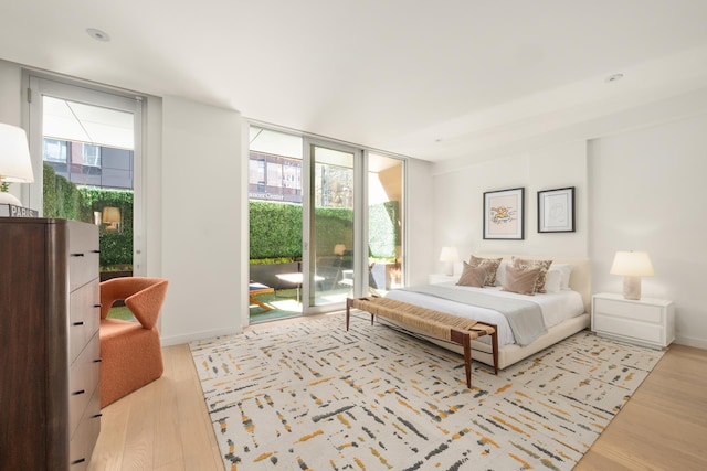 bedroom with access to outside, baseboards, wood finished floors, and expansive windows
