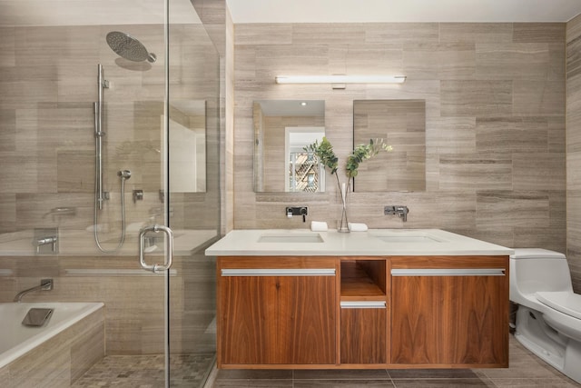 full bathroom featuring a sink, double vanity, toilet, tile walls, and tiled shower
