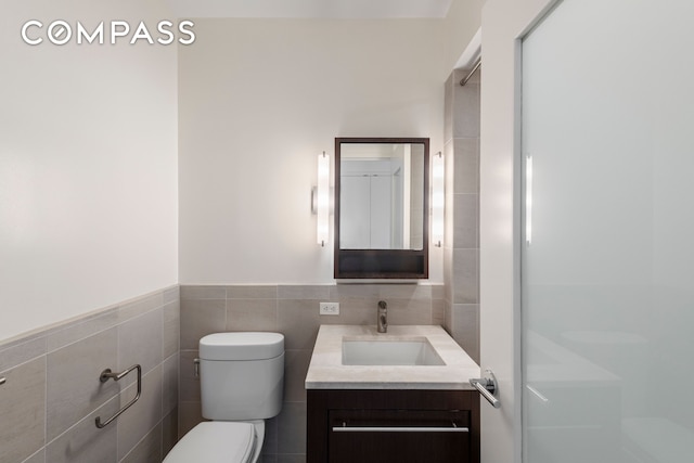 bathroom featuring tile walls, vanity, a shower stall, and toilet