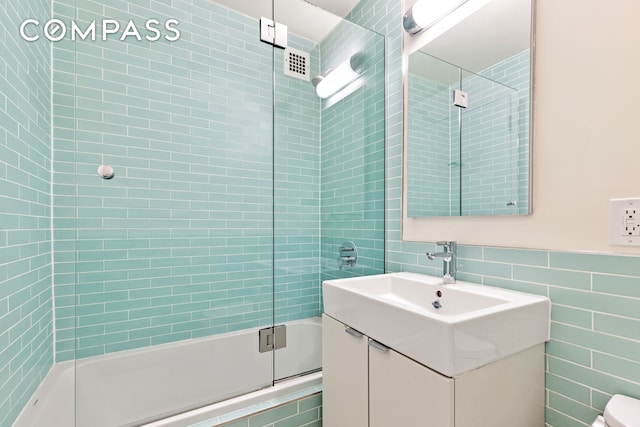 100 W 93rd St Unit 11J, New York City, NY 10025 - bathroom with tile walls, shower / bath combination with glass door, vanity, and toilet