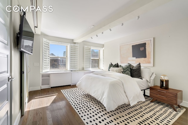 bedroom with hardwood / wood-style floors, baseboards, and beamed ceiling