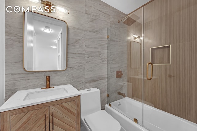 full bathroom with vanity, combined bath / shower with glass door, toilet, and tile walls