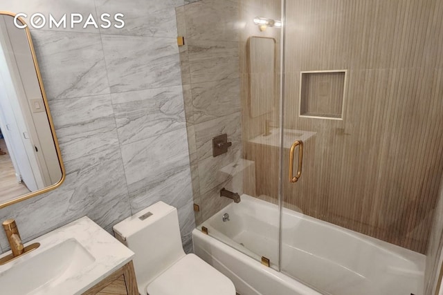 full bath featuring toilet, enclosed tub / shower combo, tile walls, and vanity