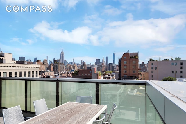 balcony with outdoor dining space and a city view