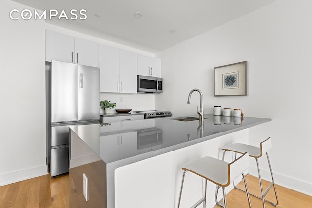 40 Schaefer St Unit 3R, New York City, NY 11207 - kitchen featuring a peninsula, baseboards, a kitchen breakfast bar, a sink, and appliances with stainless steel finishes