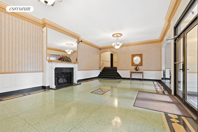 building lobby featuring wallpapered walls, wainscoting, crown molding, and stairway
