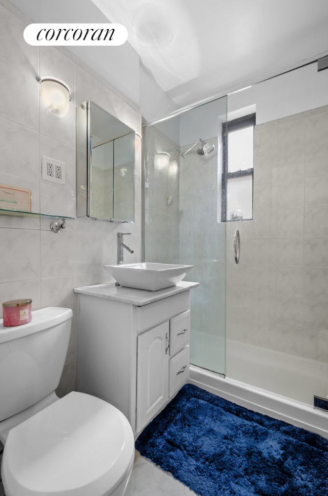 full bathroom featuring a shower stall, vanity, toilet, and tile walls