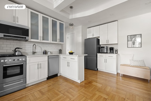 kitchen with white cabinetry, stainless steel appliances, light countertops, and a sink