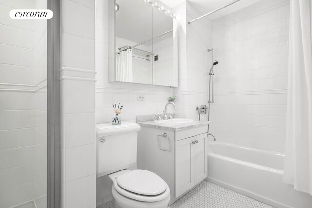 425 5th Ave Unit 22F, New York City, NY 10016 - bathroom featuring shower / bath combo with shower curtain, toilet, vanity, tile patterned floors, and tile walls