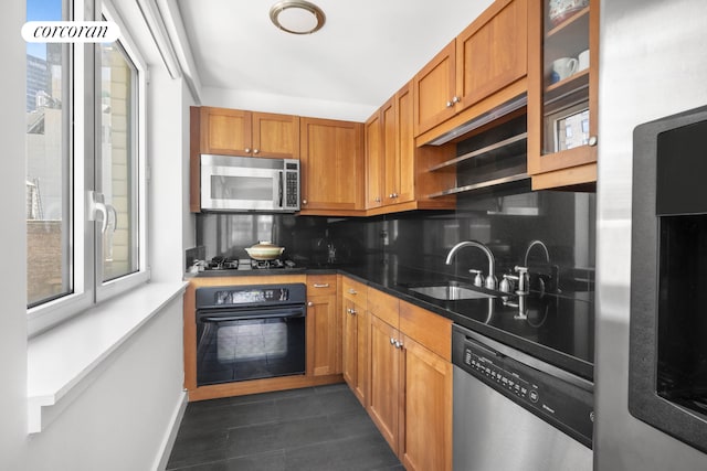 425 5th Ave Unit 22F, New York City, NY 10016 - kitchen featuring stainless steel appliances, a sink, decorative backsplash, dark tile patterned floors, and brown cabinets