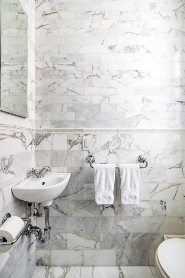 114 E 84th St Unit 8B, New York City, NY 10028 - half bathroom featuring toilet, tile walls, and a sink