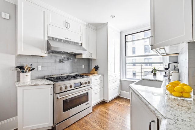 114 E 84th St Unit 8B, New York City, NY 10028 - kitchen featuring white cabinetry, tasteful backsplash, under cabinet range hood, and stainless steel stove