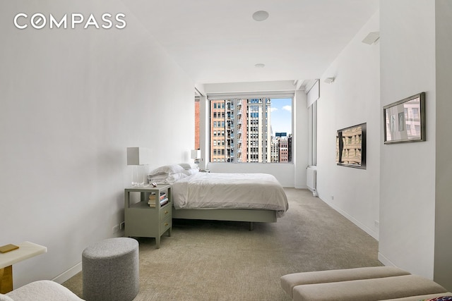 bedroom with radiator, light colored carpet, and baseboards