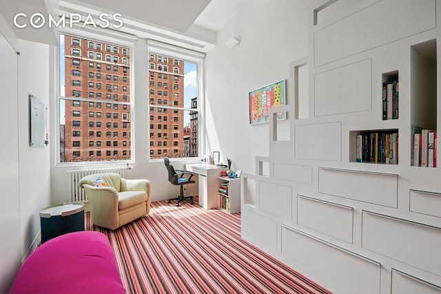 living area featuring baseboards, radiator, and carpet