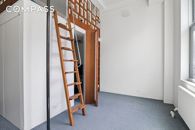 hallway with radiator, carpet floors, and baseboards