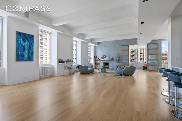 living room featuring radiator heating unit, wood finished floors, plenty of natural light, baseboards, and beamed ceiling