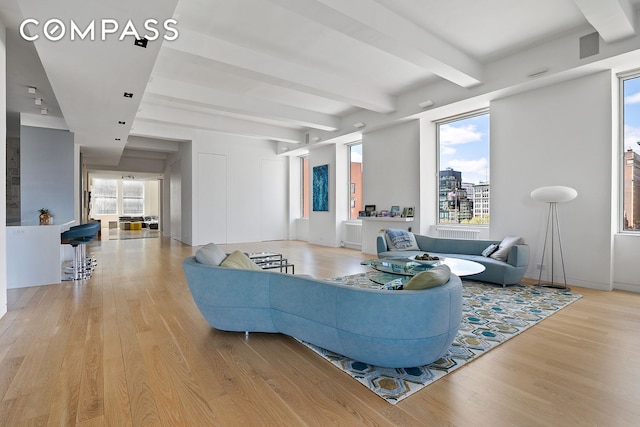 living room with beamed ceiling, light wood-type flooring, and baseboards