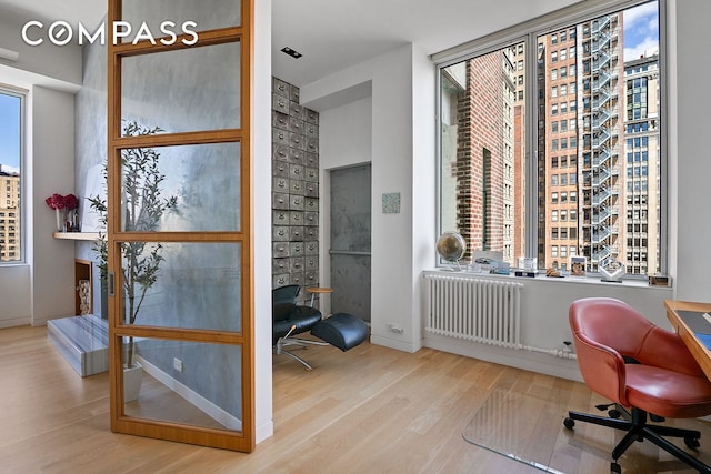 office with wood finished floors, radiator, and plenty of natural light